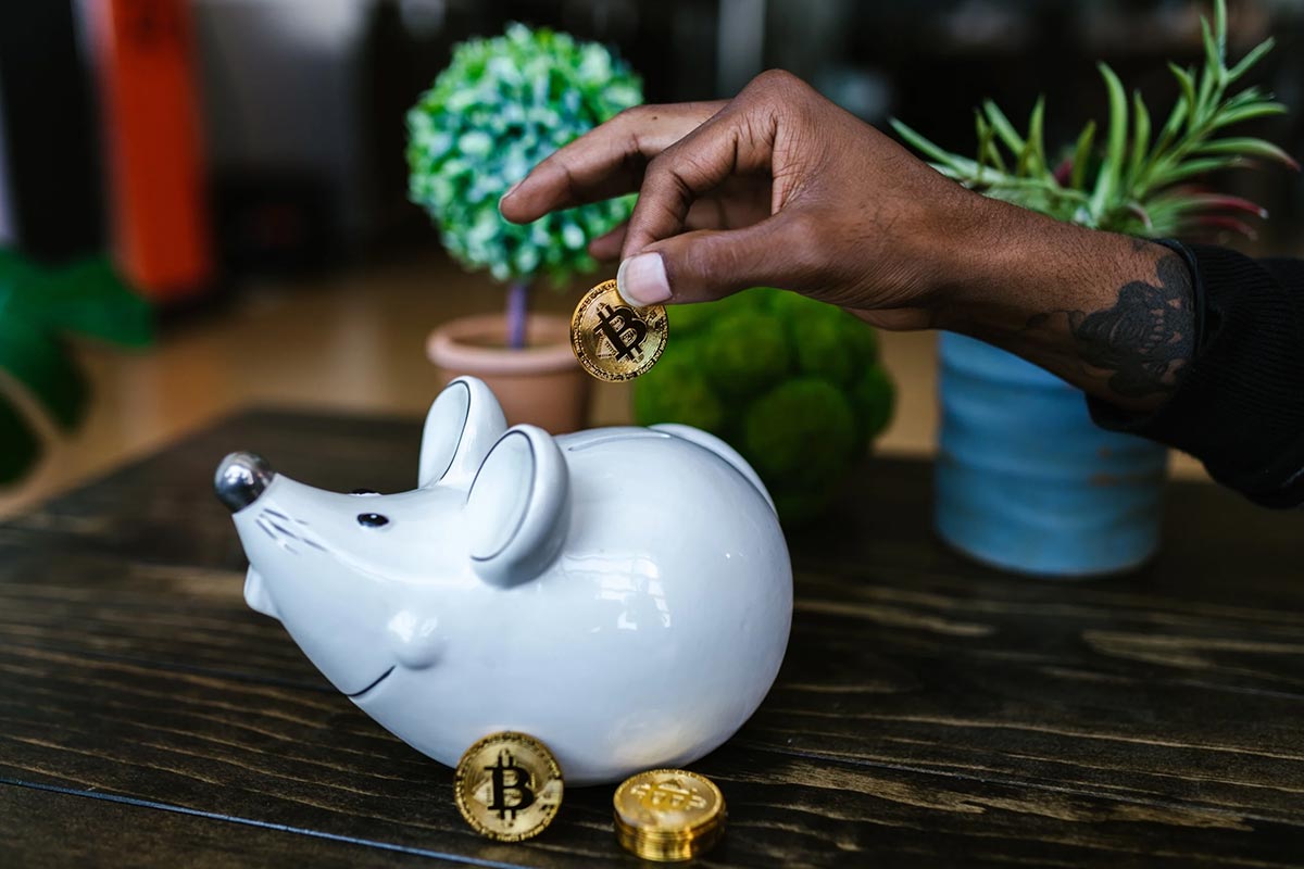 A Person Putting Bitcoin in a Piggy Bank.
